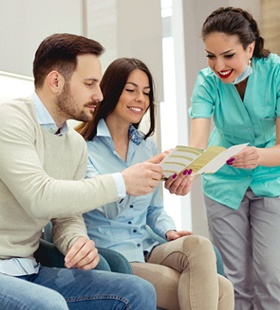 A dental team member showing a couple a brochure