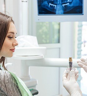 Dentist showing woman a dental implant model