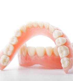 An up-close image of a full set of dentures created for an individual with missing teeth along the top and bottom arches