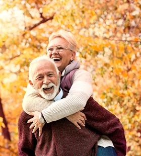 An older couple smiling and playing together while outside