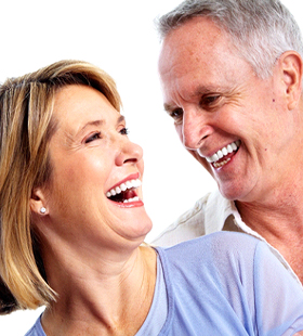 An older man and woman laughing and smiling after receiving their custom-made dentures