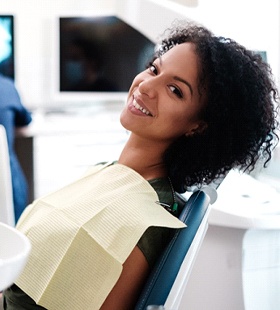 A young female seated in the dentist’s chair preparing for a checkup and cleaning 