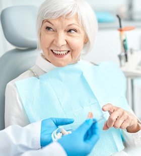 An older woman talking to her dentist about dental implant care in Delafield