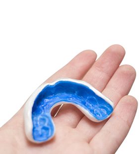A person holding a custom-made mouthguard in their hand