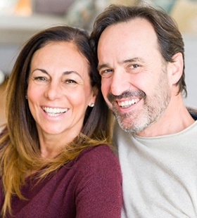 A happy middle-aged couple smiling and pleased with the results of their implant-supported bridges