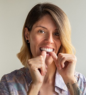 Woman inserting Invisalign aligner into her mouth