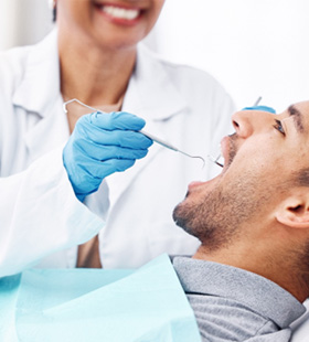 Dentist checking male patient’s mouth 