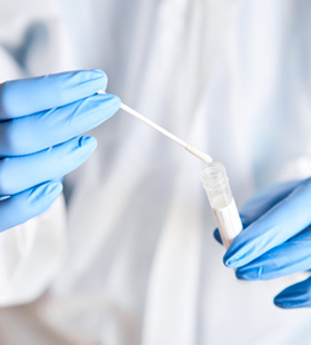 Person placing a used swab in a tube for analysis 