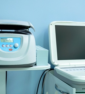 A centrifuge and laptop computer sitting in a dental office and used for Platelet Rich Fibrin