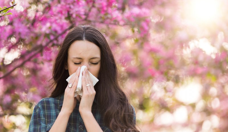 a woman blowing her nose because of allergies